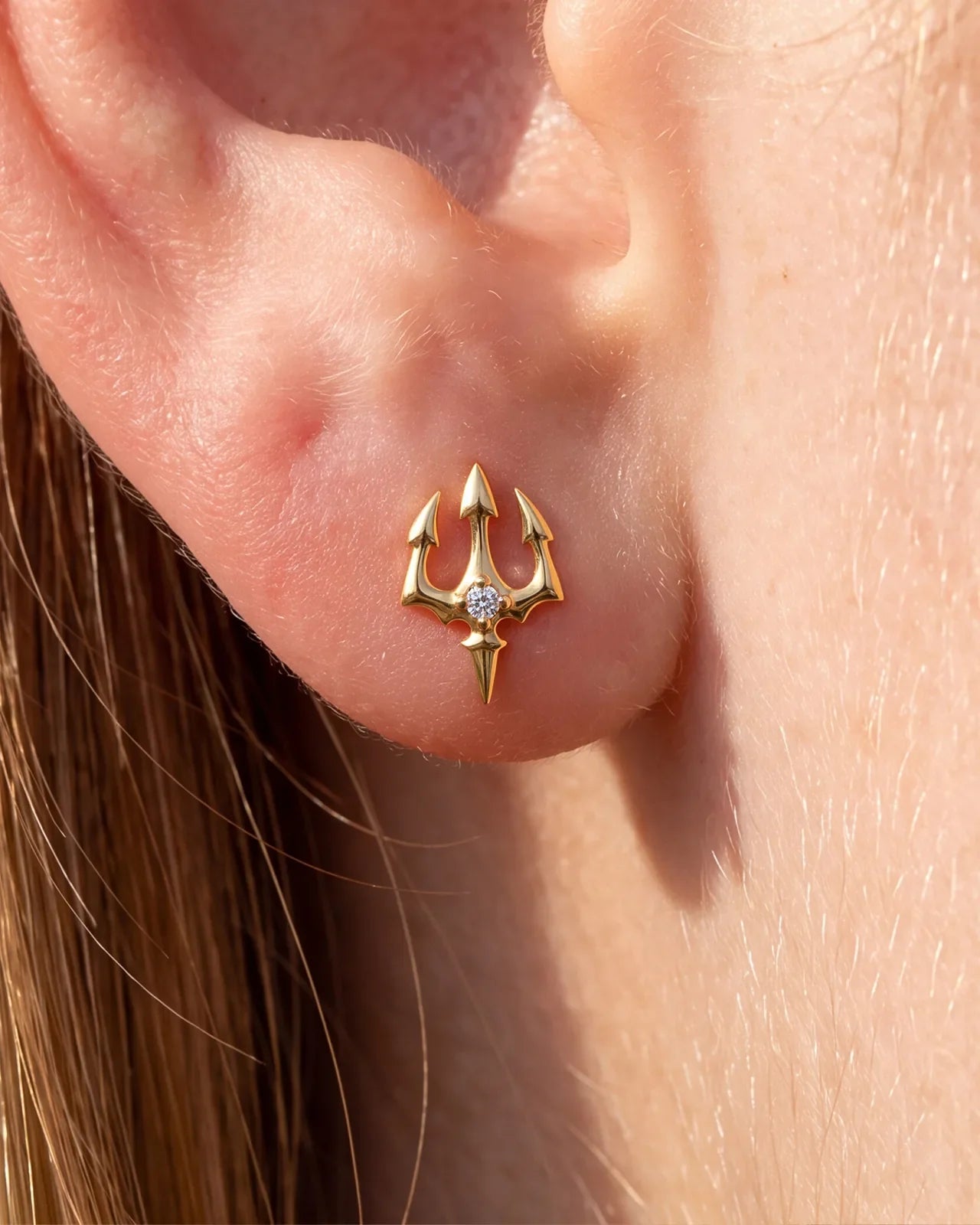 Gold trident flatback stud styled in a curated ear