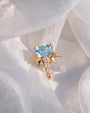 Radiant Wingcrest Flatback Stud, gold tone with light blue center stone, styled product view