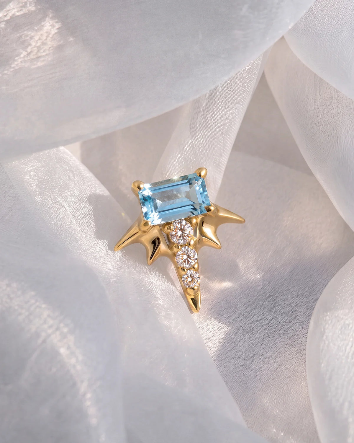 Radiant Wingcrest Flatback Stud, gold tone with light blue center stone, styled product view